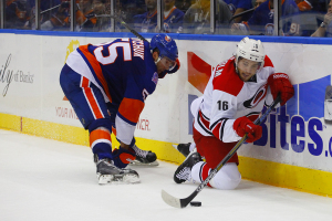 Carolina Hurricanes Elias Lindholm handles the puck after getting knocked down by NY Islanders Defenseman Johnny Boychuck. (Brandon Titus/Inside Hockey)