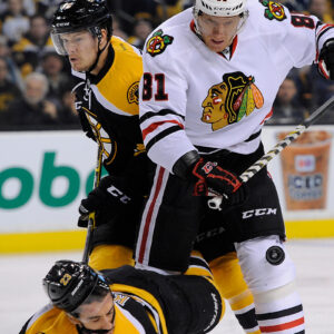 Boston Bruins center Chris Kelly (23) takes a hit from Chicago Blackhawks right wing Marian Hossa (81) in front of the goal.