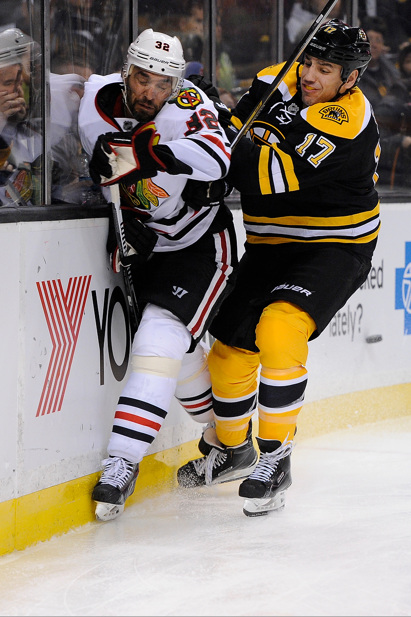 Boston Bruins left wing Milan Lucic (17) hits Chicago Blackhawks defenseman Michal Rozsival (32).