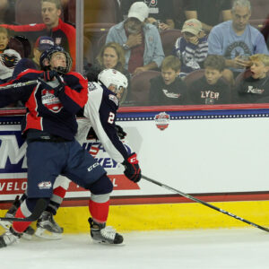 Josh Maniscalco (#5 - Blue) collides with Mikey Anderson (#2 - White) along the boards