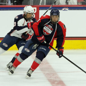 Mick Messner (#12 - Blue) turns with the puck while being pursued by Sasha Chmelevski (#19 - White)