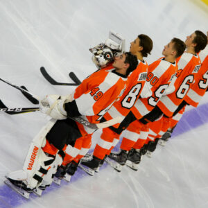 Members of the Philadelphia Flyers lineup on the blue line during the national anthem