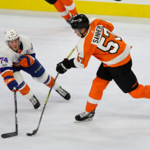 Defenseman Travis Sanheim (#57) of the Philadelphia Flyers shoots the puck against a defending Right Wing Travis St. Denis (#74) of the New York Islanders